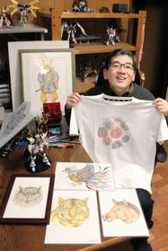 これまでの作品を前にニューバランスのＴシャツを持つ田寺誠人さん＝明石市