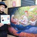 作品展で展示する絵画のそばで新作絵本を手にするたなかしんさん＝明石市貴崎２