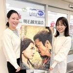 ポスターを手に明石城跡で撮影された映画をＰＲする明石観光協会の前川さん（左）と福田さん＝明石市東仲ノ町