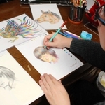 創作中の田寺さん。「配色のバランスを考えながら描いています」＝明石市