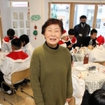 中学生と高齢者を訪問した師走。円卓の間に立つ松本茂子さん＝明石市西明石南町２