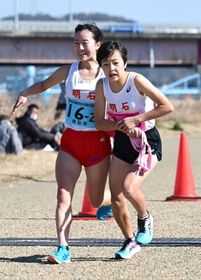女子・明石市の２区西尾わこと選手（左）からたすきを受け取る３区大神彩羽選手＝加古川市加古川町河原、加古川河川敷マラソンコース
