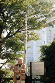 子午線を示す「トンボの標識」と写真に納まる松本さん。宇宙に関心を持つきっかけになった（天文科学館提供）