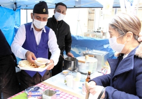 屋台で来客にカレーとナンを手渡すガイレ・ビムさん（左）＝明石市本町１