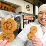 「お世話になりました」の焼き印入りせんべいを手にする富士の山菓舗７代目の原田岳秋さん。「愛」の焼き印入りはバレンタインデーやホワイトデーの贈り物にぴったりという＝明石市本町１