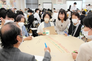 タウンミーティングで意見を交わす参加者ら。丸谷聡子市長（中央右）も各グループを巡った＝明石市東仲ノ町