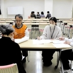 被災者役（手前）から生活環境などを聞き取る参加者たち＝明石市貴崎１