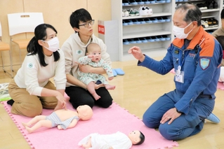 講師（右）から乳幼児の心肺蘇生法などを学ぶ参加者＝明石市大明石町
