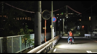 明石市東朝霧丘の坂道で撮影された映画の一場面。奥に明石海峡大橋が輝く（（Ｃ）ノブ・ピクチャーズ）