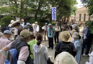 林神社の境内で牧野満徳さん（中央）の話を聞く参加者ら＝明石市宮の上