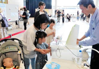 熱中症予防ブースで湿度体感機を体験する親子＝あかし市民広場