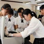 実験でサンプルを遠心分離機に入れる生徒ら＝明石北高校