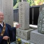 空襲犠牲者の墓の前に立つ松尾義康さん＝明石市上ノ丸１