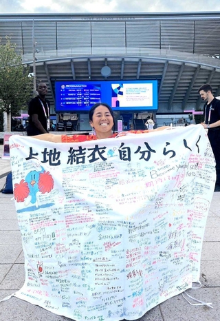 パリ・パラリンピックへ向けて地元住民らが寄せ書きした旗を持つ上地結衣選手（シィメス提供）
