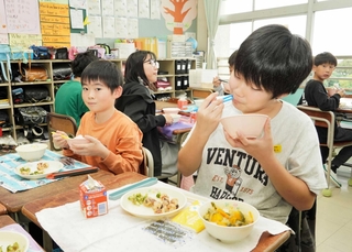 有機食材や明石の海産物をふんだんに使った給食を頰張る児童ら＝明石市明南町３