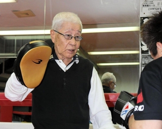 生徒のミット打ちを受ける吉田欽哉会長＝明石市荷山町