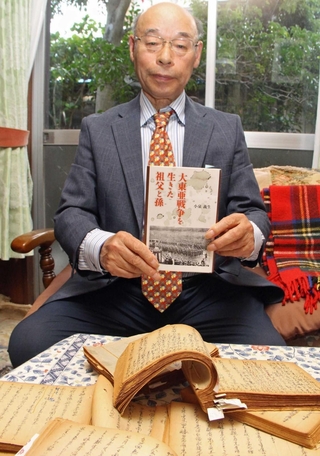 祖父が残した日記を前に、著書を持つ小泉義生さん＝神戸市西区