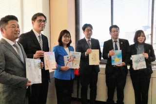 リユースした絵本を丸谷聡子市長（左から３人目）に手渡した関係者ら＝明石市役所
