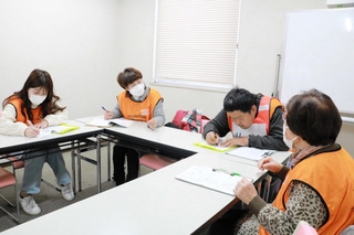 被災者役（右）の女性からニーズを聞き取るボランティア役の参加者たち＝明石市立総合福祉センター