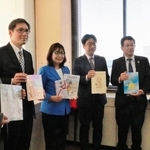 リユースした絵本を丸谷聡子市長（左から３人目）に手渡した関係者ら＝明石市役所