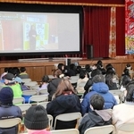 地域住民らが阪神・淡路大震災の体験を語る動画を見る子どもや保護者ら＝江井島小学校