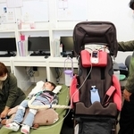 訓練で、明石医療センターから医療機器への電源の供給を受ける太田メリサさん（中央）と家族＝明石市大久保町八木