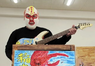 紙芝居を使った防災活動に取り組む福石健一さん。エレキギターで効果音を出す＝明石市内