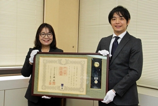丸谷聡子市長（左）から紺綬褒章を伝達された裙本理人さん＝明石市役所
