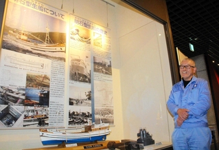 明石型生船の模型のそばに立つ金井清さん＝明石市立文化博物館