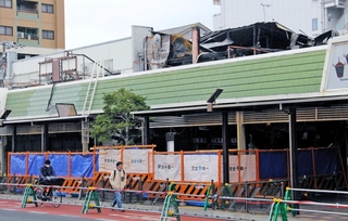 フェンスで囲まれた明石銀座商店街の火災現場。車道の一部が仮歩道となっている＝明石市内