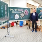 自作の黒板アートを前に話す峰崎国夫さん＝大久保北コミセン