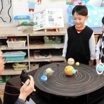 井上毅館長（左）に太陽系惑星の模型について説明する園児ら＝播陽幼稚園