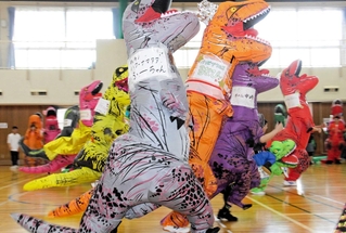 恐竜の着ぐるみを着て走る参加者ら＝明石市立勤労福祉会館