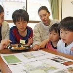 庭園の完成予想図を眺める堀美香さん（左）ら。皿の料理はカフェの試作メニュー＝明石市南貴崎町