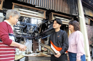 激しく焼けた店舗の前に立つ（左から）森本晃司さんと絢斗さん、まゆみさん＝明石市本町１