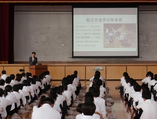 生徒らを前に、戦没者の遺骨収集の取り組みについて話す藤森龍さん＝二見中学校