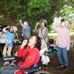 団子を食べるポーズで体を動かす参加者ら＝県立明石公園