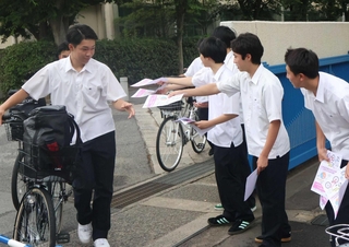 自転車で登校した生徒にチラシを渡し、注意を呼びかける生徒会役員ら＝明石商業高校