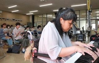 多久島晶子さんの演奏に合わせて口ずさむ参加者ら＝明石市沢野１