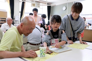 スクールガードのボランティアらに飲み物などを提供する児童＝谷八木小学校