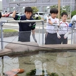 ヒラメに餌をやる中学生たち＝明石市二見町南二見