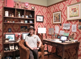 自身のアトリエを再現したコーナーで、特別展への思いを語るたなかしんさん＝明石市立文化博物館