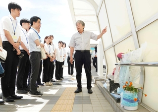 事故現場となった歩道橋で、新入職員へ当時の状況などを語る下村誠治さん＝明石市大蔵海岸通１
