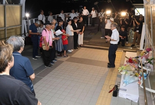 慰霊碑の前で鎮魂歌を歌う市民有志ら。献花に訪れた遺族も耳を傾けた＝２１日夜、明石市大蔵海岸通１（撮影・丸山桃奈）