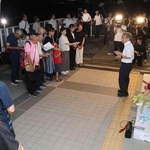 慰霊碑の前で鎮魂歌を歌う市民有志ら。献花に訪れた遺族も耳を傾けた＝２１日夜、明石市大蔵海岸通１（撮影・丸山桃奈）