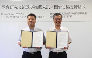 署名した協定書を手に持つ（左から）神戸大学の臼井英之システム情報学部長と明石高専の土居信数校長＝明石市魚住町西岡