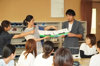 「あかし保育絵本士」の養成講座で、自身の経験を紹介する受講者と講師の松本崇史園長（右）＝明石市大明石町１