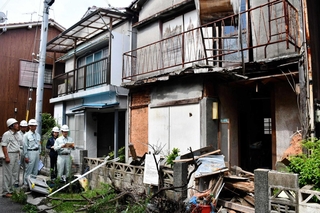 倒壊の危険性がある空き家（手前）を取り壊すため、行政代執行を宣言する市職員＝２０１８年８月、明石市東藤江１