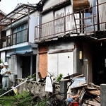 倒壊の危険性がある空き家（手前）を取り壊すため、行政代執行を宣言する市職員＝２０１８年８月、明石市東藤江１