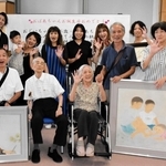 作品展の会場で親族に囲まれる井登延和さん（前列左から３人目）と慧さん（同２人目）＝ふれあいプラザあかし西